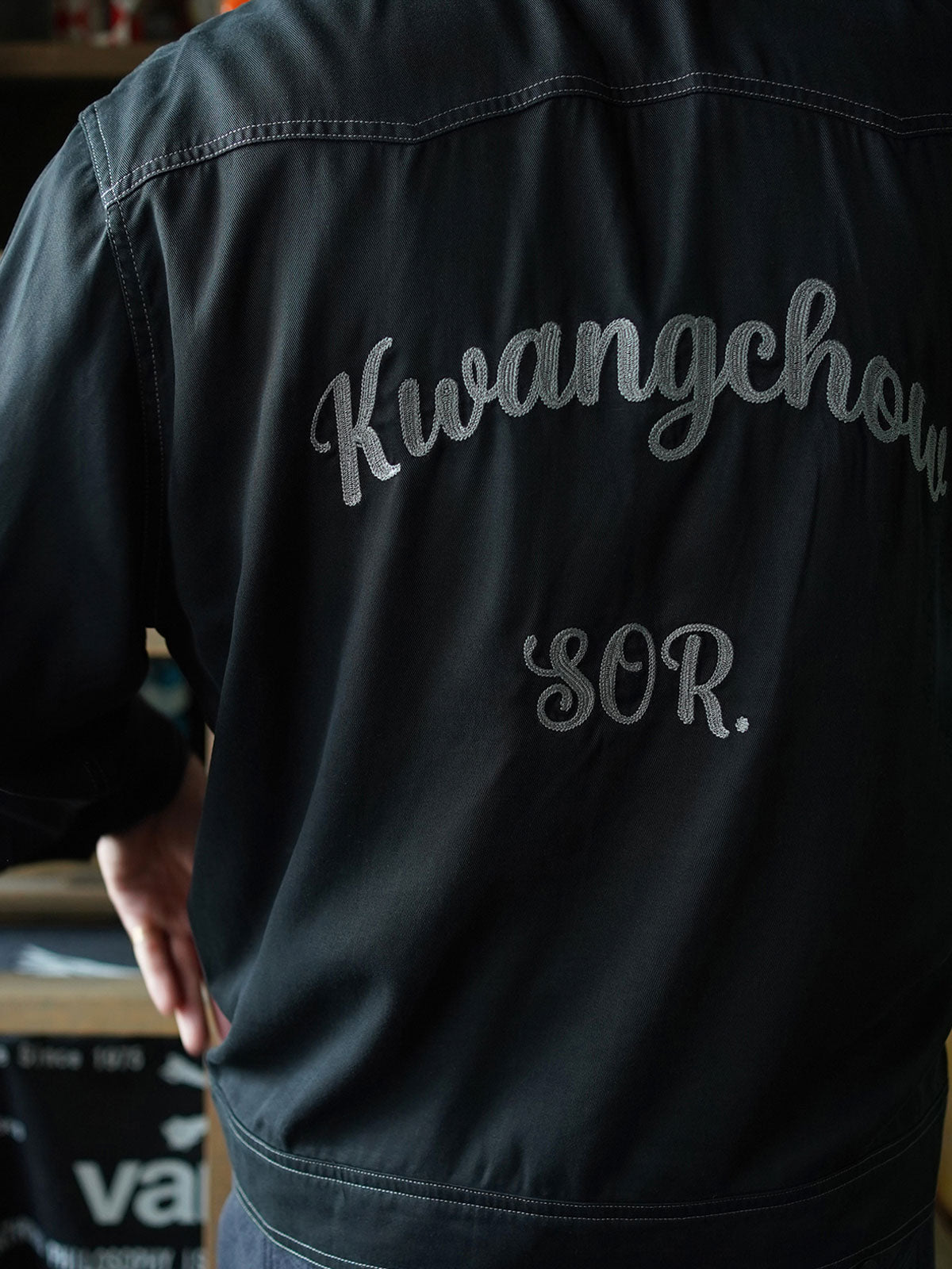 詳細画像: 背面の「広州 Kwangchow」刺繍とコントラストステッチのディテール、ヴィンテージ風デザイン
モデル画像: テンセルコットンツイル生地のショート丈アメリカンウエスタンシャツ着用イメージ