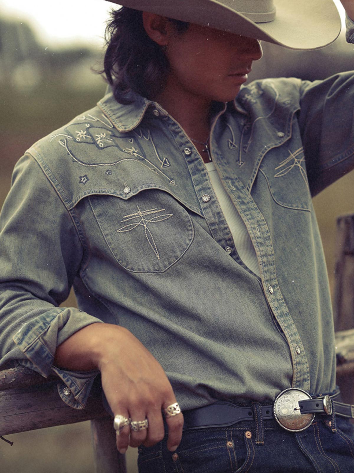 詳細画像: ジグザグ型肩部デザインと二色刺繍のディテール特写。高級感と遊び心を兼ね備えたディテール。
モデル画像: モデルが着用したウェスタン風ヴィンテージデニムシャツ。ギャンブラー精神とレトロなカウボーイスタイルを表現したスタイリング。