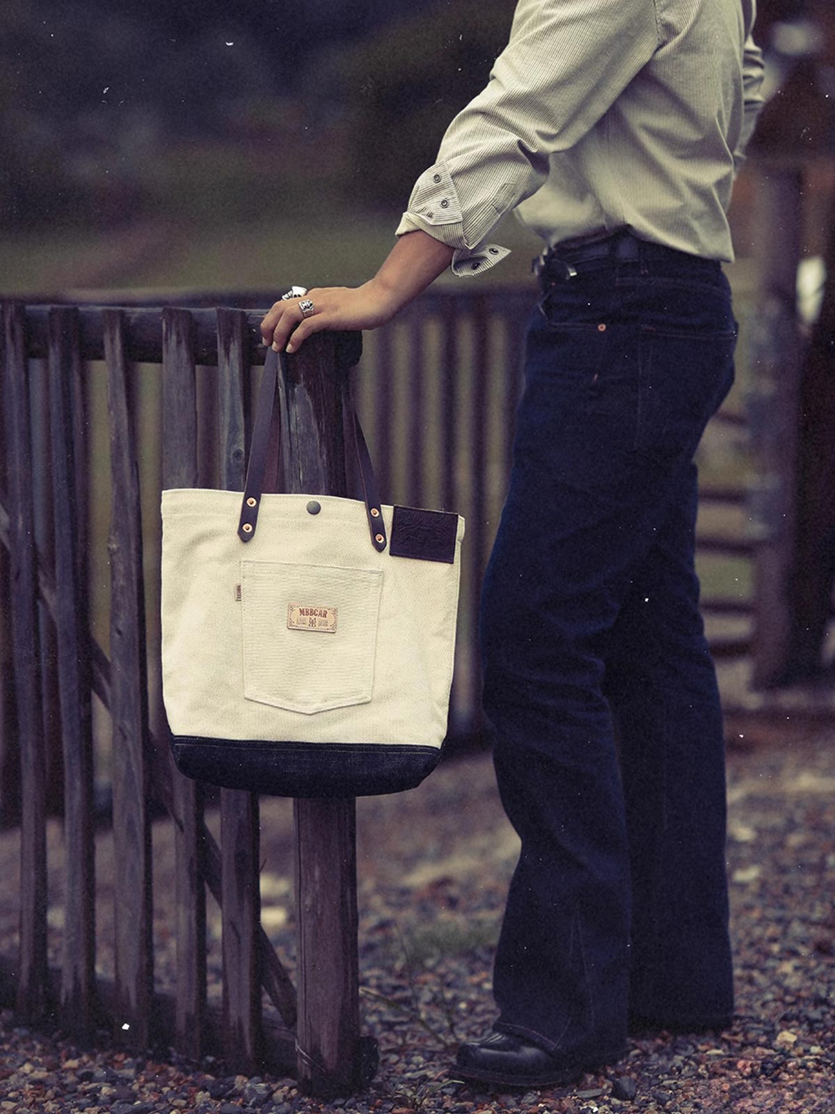 詳細画像: ベジタブルタンニンレザーストラップと前面ポケットのデザインのディテール - 機能性とスタイル
モデル画像: モデルがホワイトキャンバスと赤耳デニムのショルダーバッグを持つ姿 - 日常使用に適したファッションアイテム