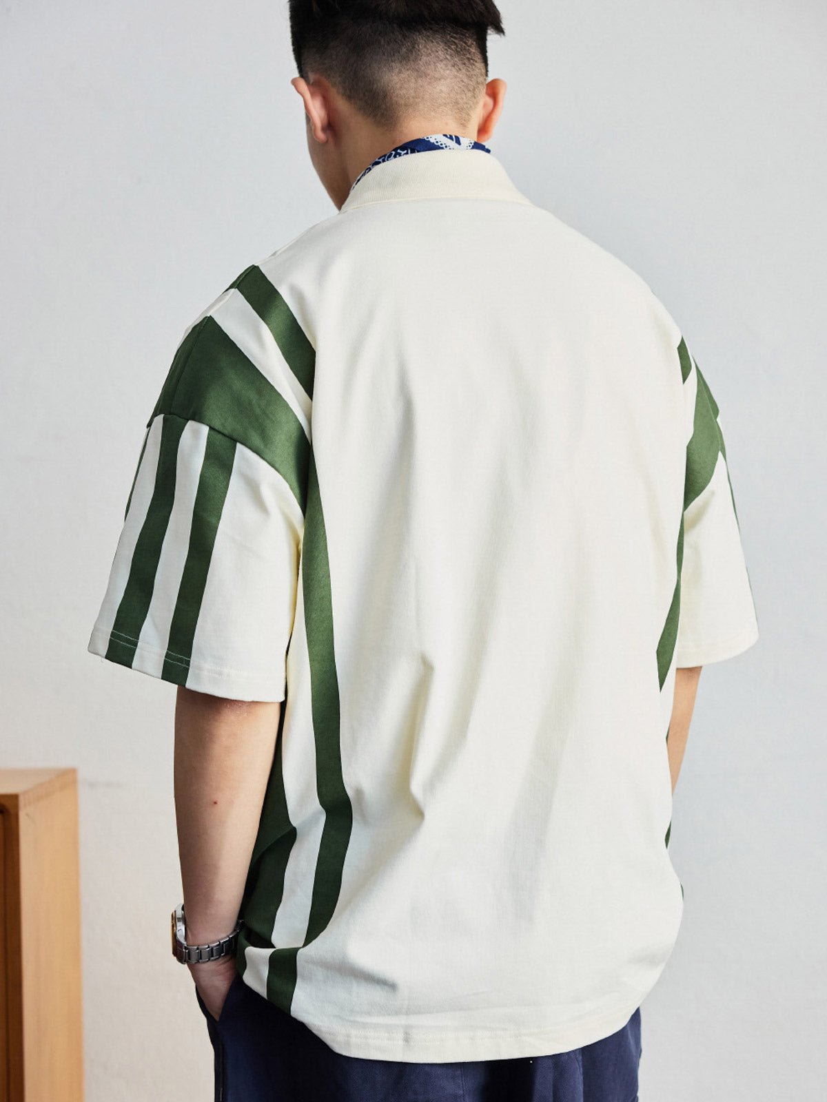 ポロシャツの草緑色ボタンと襟のディテールを特集し、洗練された作りを示す。