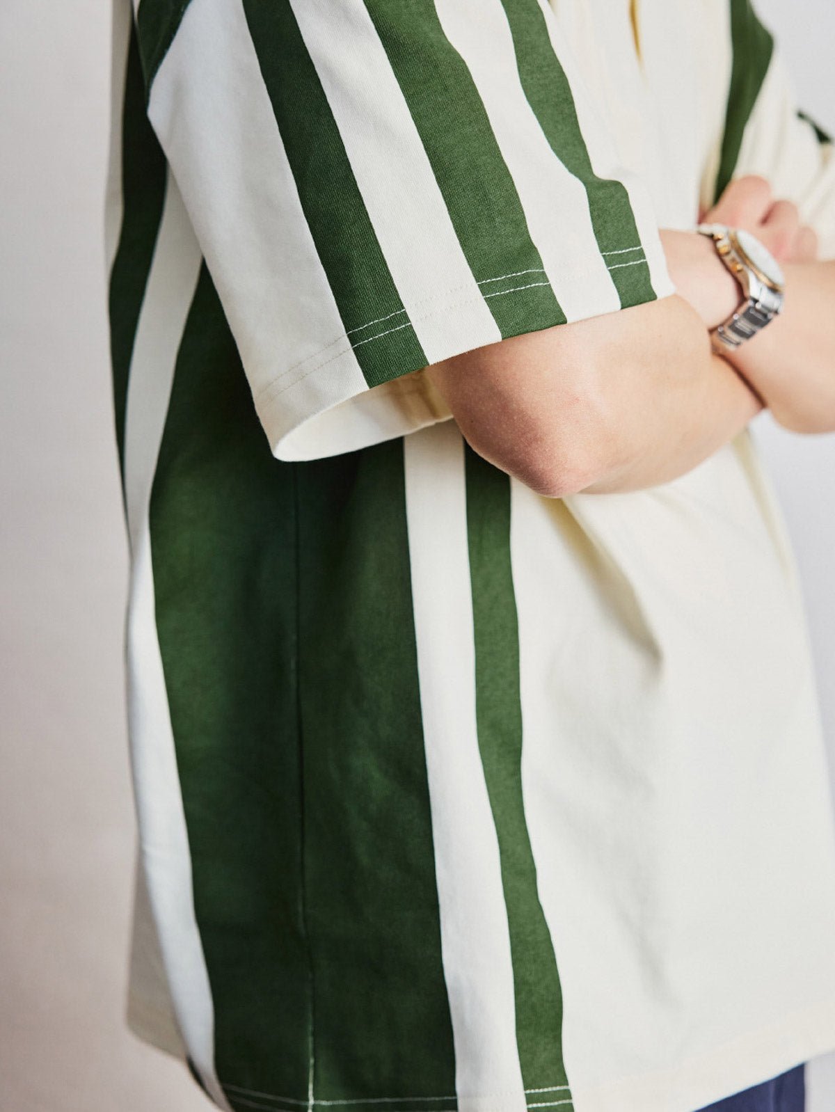 ポロシャツの草緑色ボタンと襟のディテールを特集し、洗練された作りを示す。