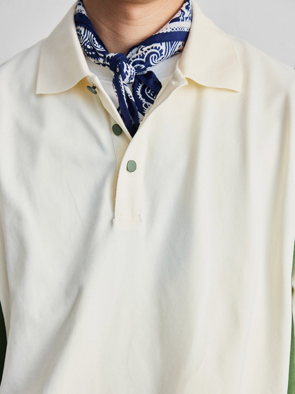 ポロシャツの草緑色ボタンと襟のディテールを特集し、洗練された作りを示す。
