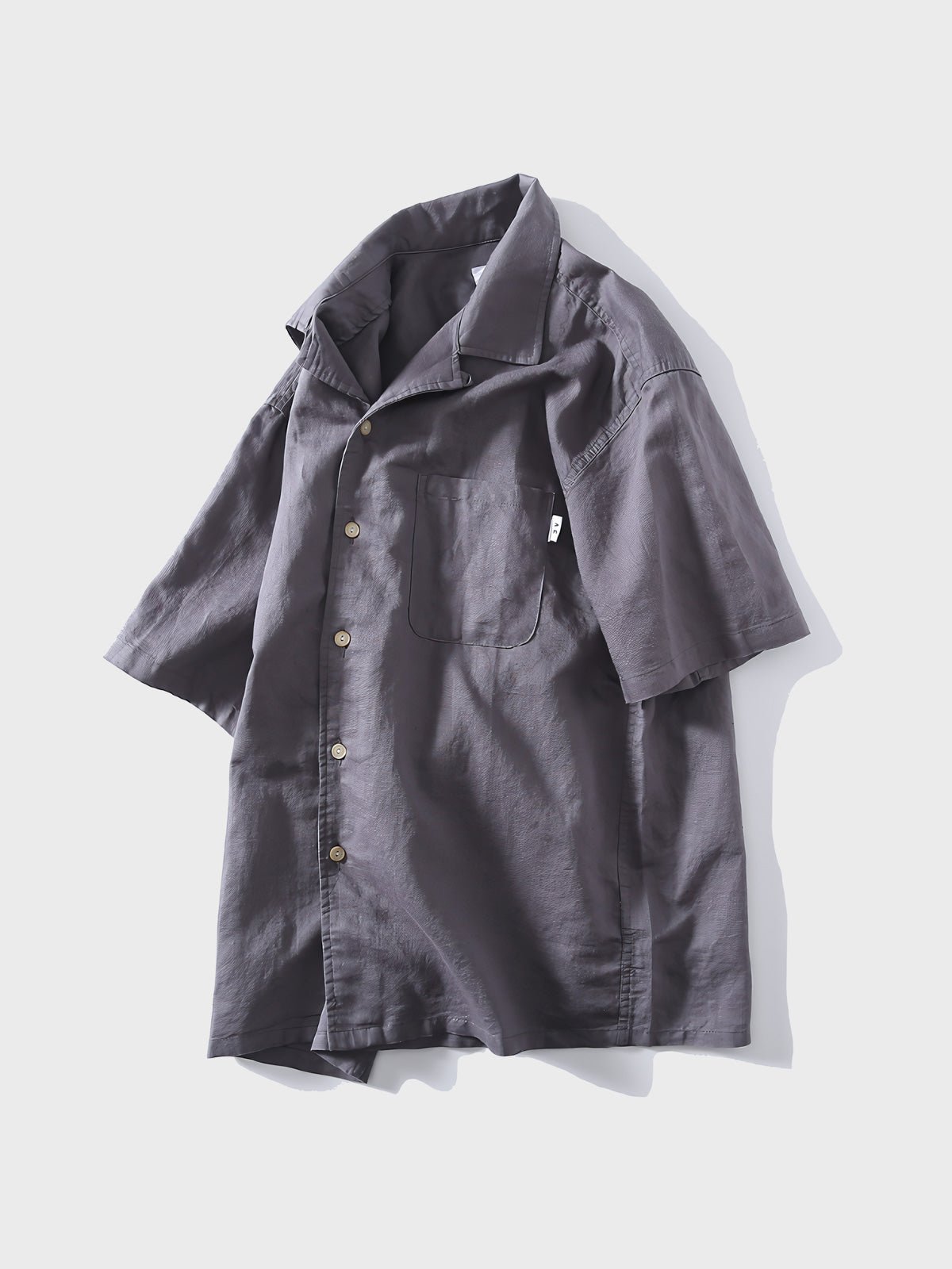 グレーのキューバカラーリネン半袖シャツ、ミニマリスティックなデザイン。