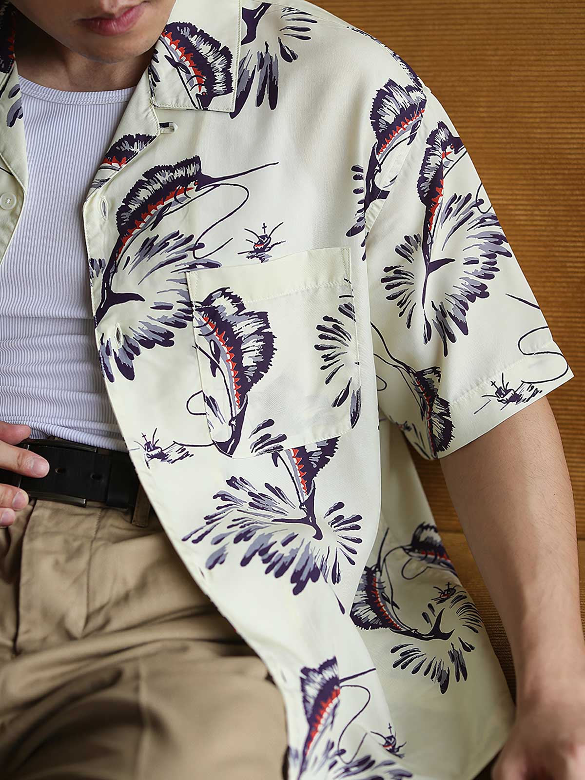 モデルがカジキプリントのハワイアンシャツを着用し、リラックスした夏のスタイリングを展示しています。