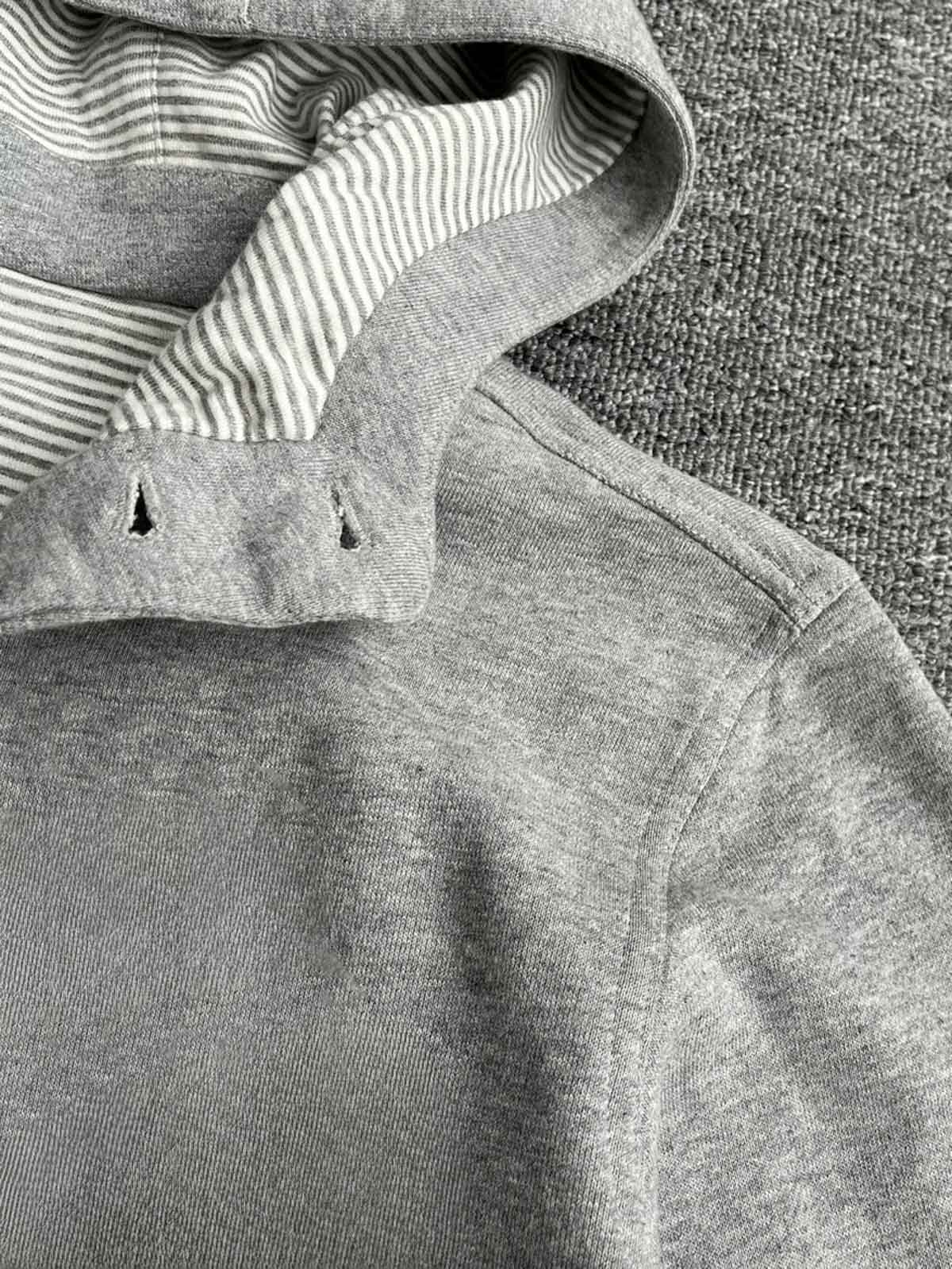 製品画像: クラシックグレーのコットンフーディージャケット、シンプルなデザイン、正面の平置き写真
詳細画像: スナップボタンとフードのディテール特写、機能性とデザインの完璧なバランス