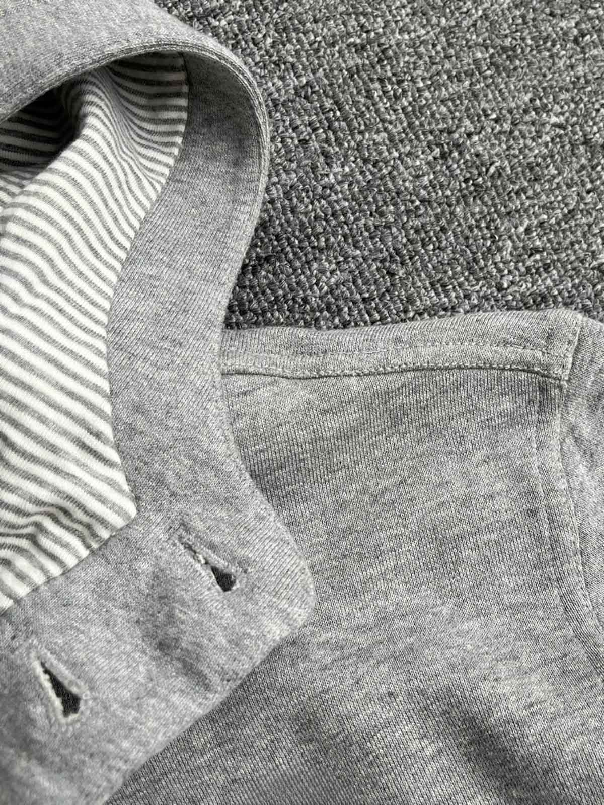 製品画像: クラシックグレーのコットンフーディージャケット、シンプルなデザイン、正面の平置き写真
詳細画像: スナップボタンとフードのディテール特写、機能性とデザインの完璧なバランス