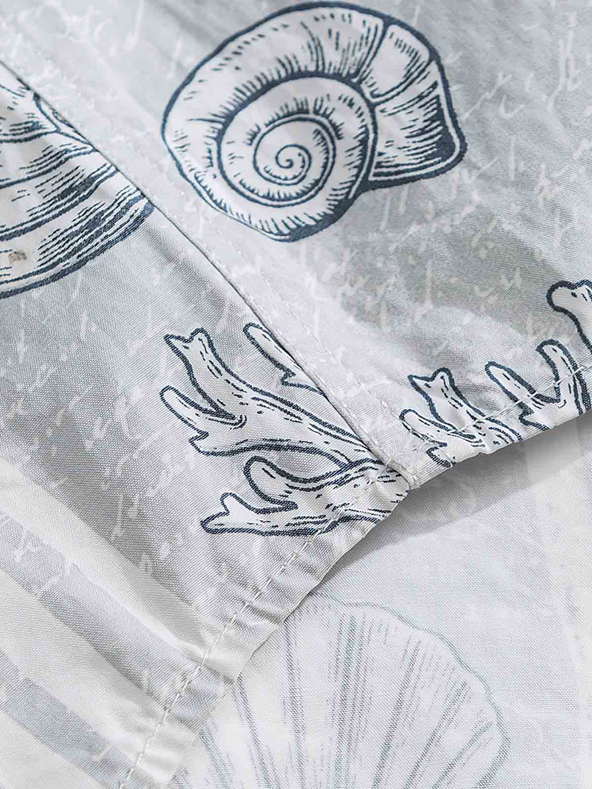 貝殻プリント半袖シャツの精巧なプリントパターンのクローズアップ。繊細な工芸技術と高品質の純綿素材が、快適な着用体験を実現します。