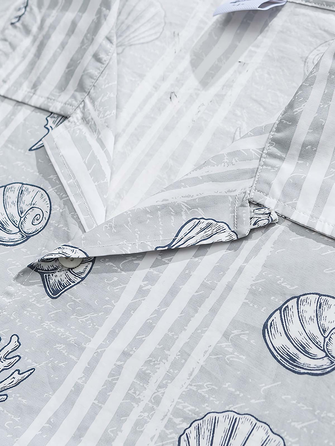 貝殻プリント半袖シャツの精巧なプリントパターンのクローズアップ。繊細な工芸技術と高品質の純綿素材が、快適な着用体験を実現します。