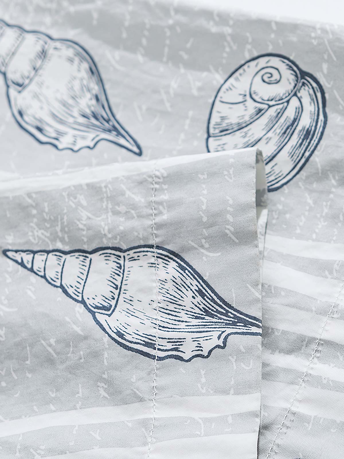 貝殻プリント半袖シャツの精巧なプリントパターンのクローズアップ。繊細な工芸技術と高品質の純綿素材が、快適な着用体験を実現します。