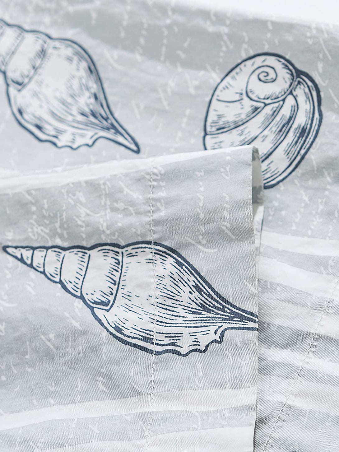 貝殻プリント半袖シャツの精巧なプリントパターンのクローズアップ。繊細な工芸技術と高品質の純綿素材が、快適な着用体験を実現します。