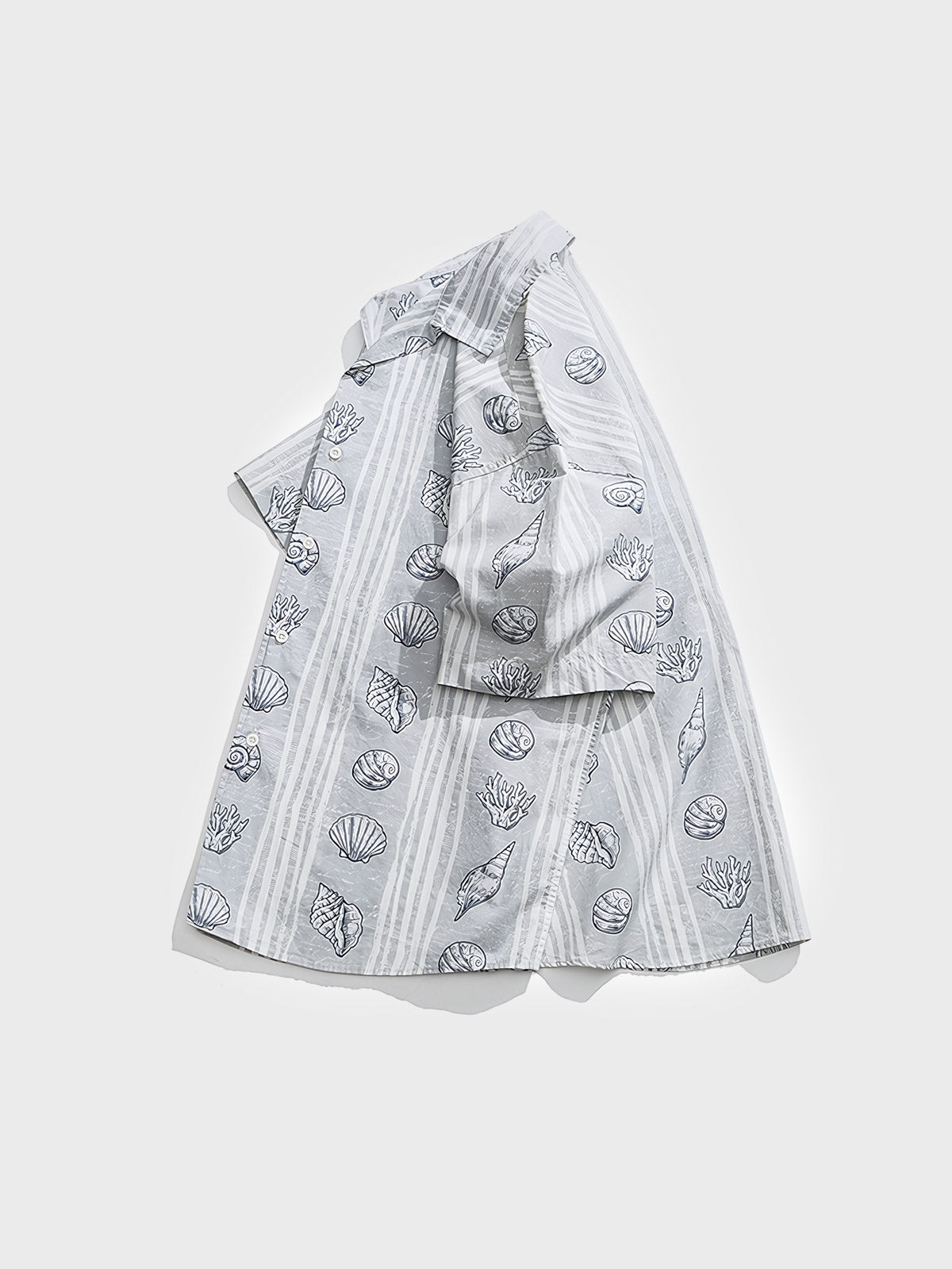 貝殻プリントが施された半袖シャツ。リラックスフィットと100%純綿の生地が特徴で、夏の涼しさと快適な着心地を提供します。」