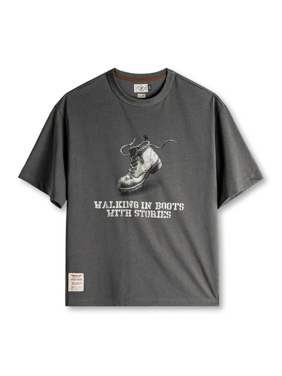 ダークグレーのTシャツ、胸に素描風のワークブーツとステンシル風の英字プリント、裾のラベル付き