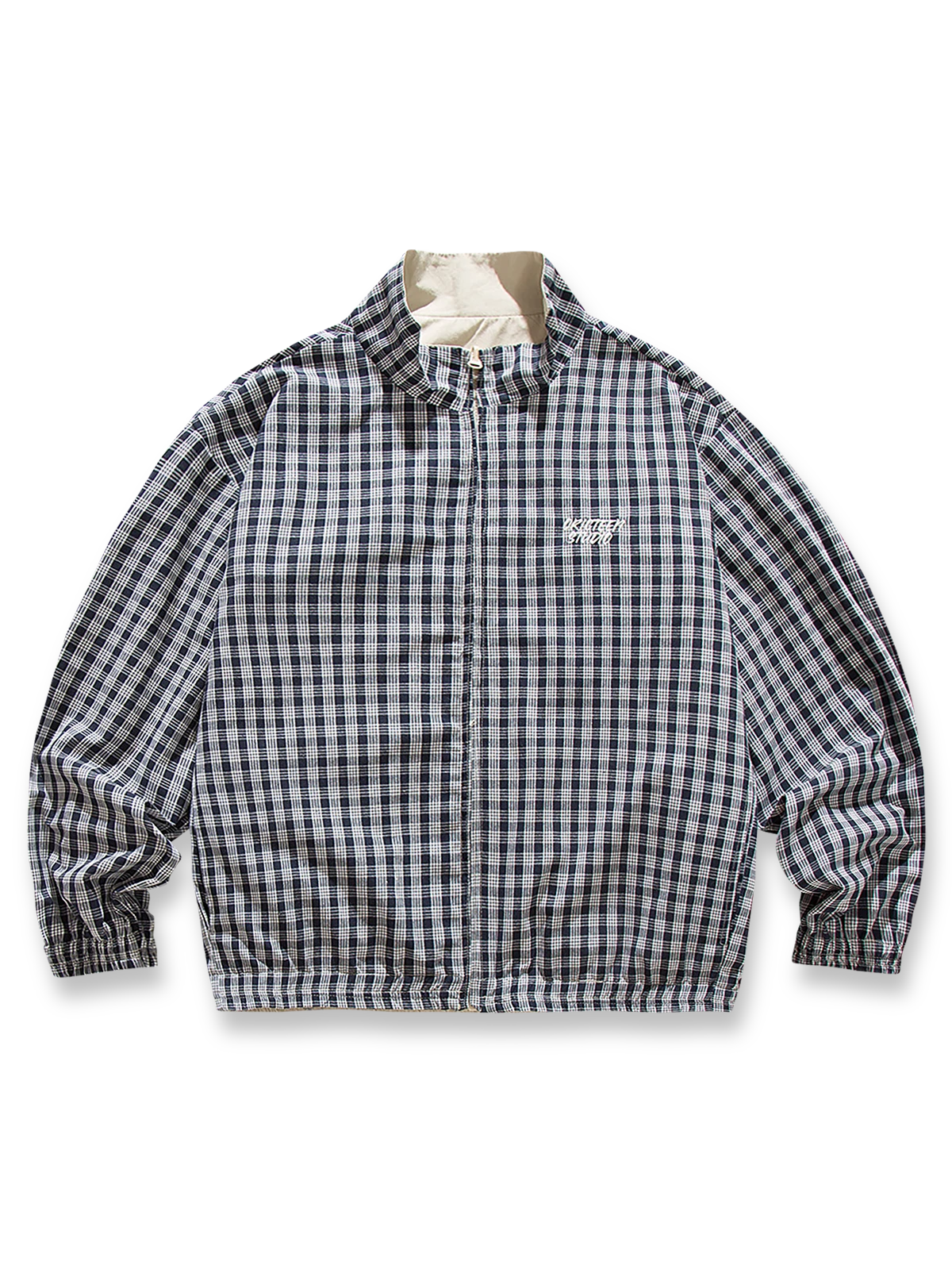 ベージュとヴィンテージチェック柄のリバーシブルスタンドカラージャケット。防風性と快適なフィット感を兼ね備え、春の多様なシーンで活躍する軽量中厚素材使用。