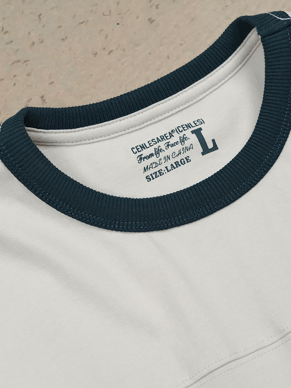 フットボールカルチャープリントTシャツの首元の小さなカラーデザインとダブルニードルショルダーラインのクローズアップ。耐久性と形状の持続性に優れたディテールが見える。