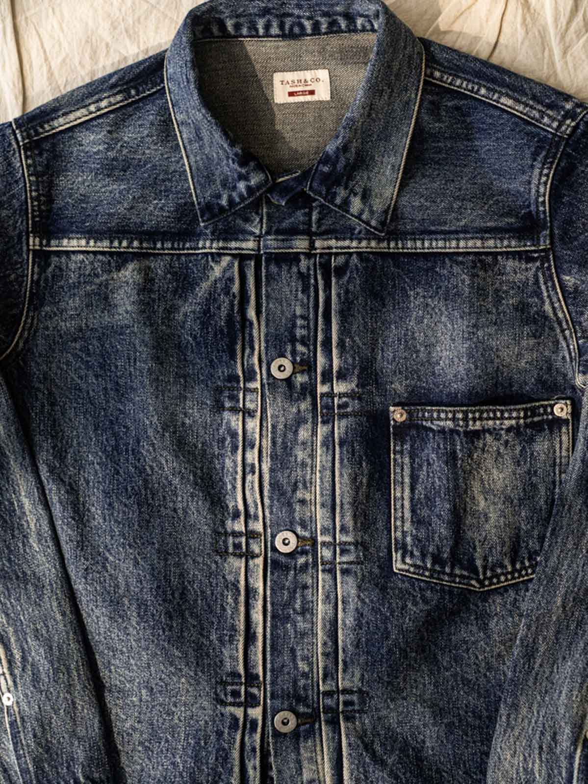 ジャケットのディテールショット、真鍮の未加工の錫メッキパリボタンとスラブデニムの質感を展示