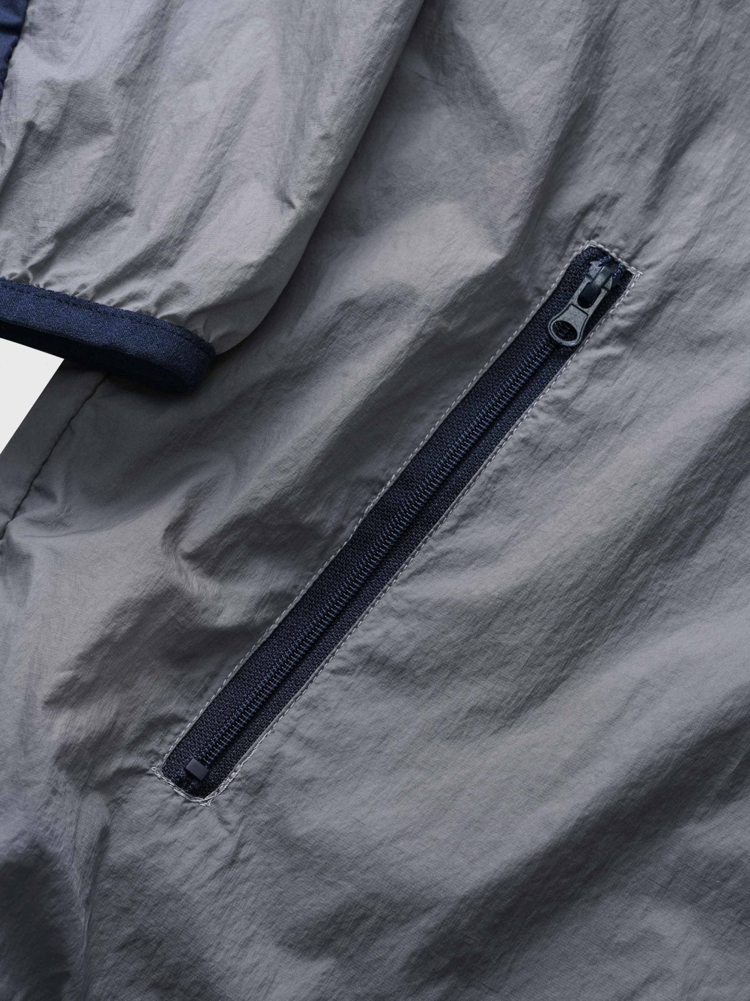 カーブ状のジッパーとサイドポケットのクローズアップ、UPF40+の紫外線対策機能を強調。