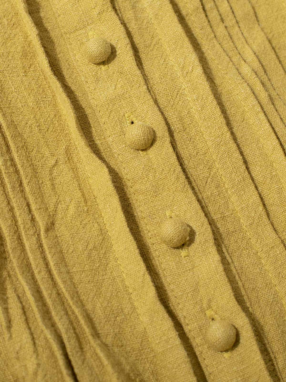 ドレスのプリーツ装飾とVネックのディテールクローズアップ