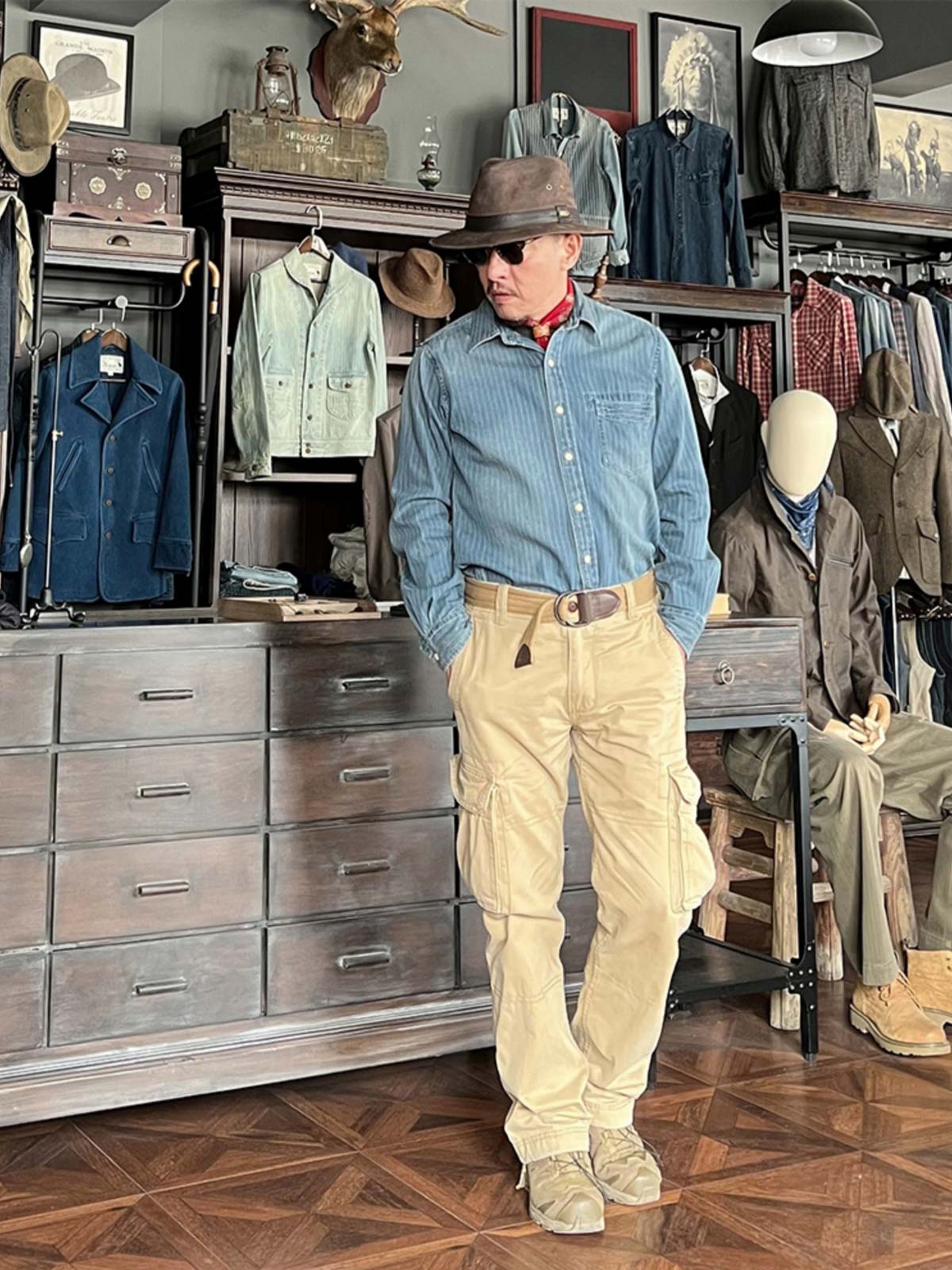 グレーや黒のカジュアルパンツと合わせた職人風ストライプデニムシャツを着用したモデル。レトロな職人の雰囲気を際立たせるスタイリング。