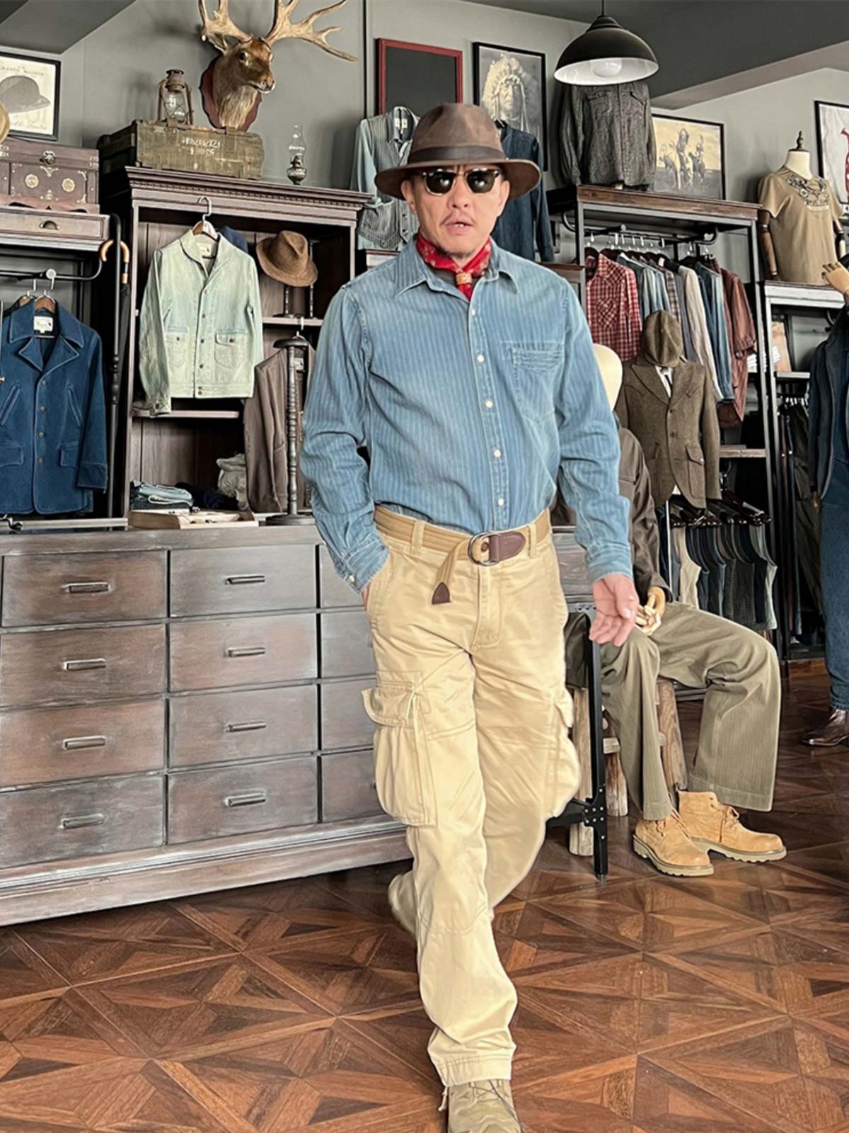 グレーや黒のカジュアルパンツと合わせた職人風ストライプデニムシャツを着用したモデル。レトロな職人の雰囲気を際立たせるスタイリング。