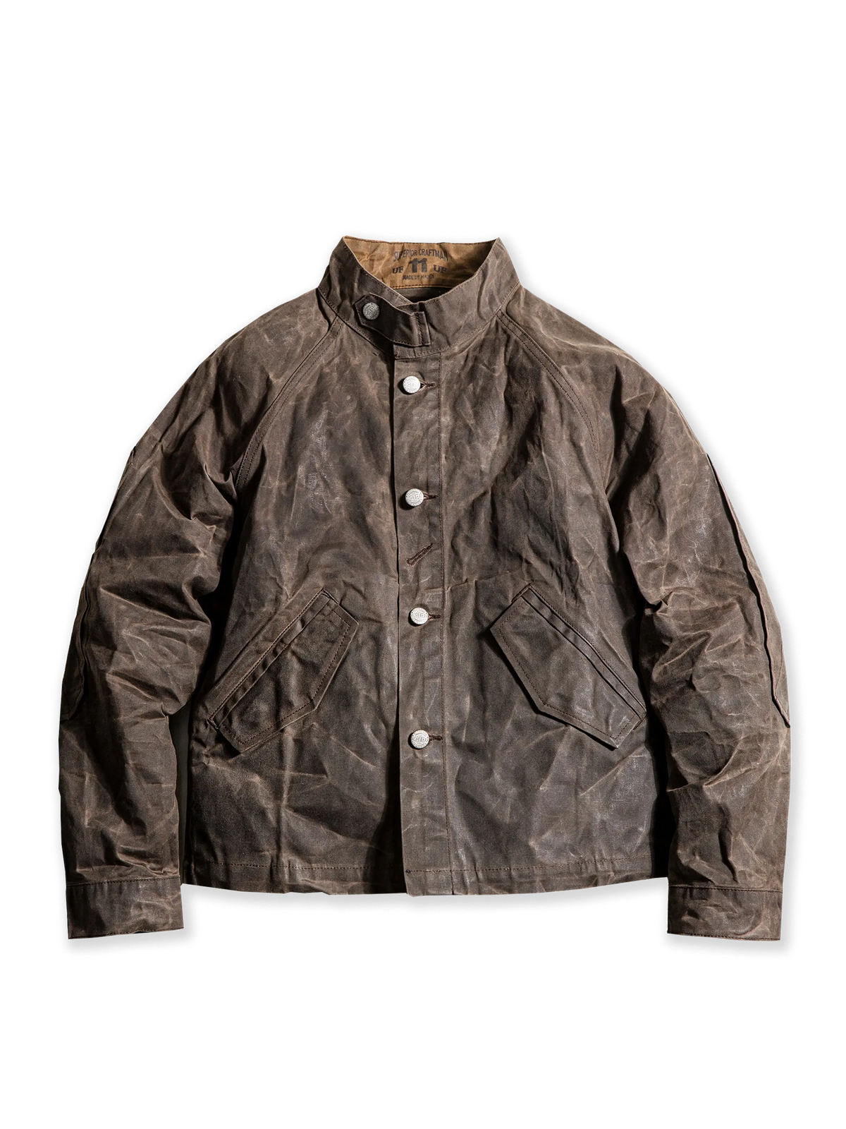 スタンドカラーとワックスドキャンバス素材を特徴とするヴィンテージミリタリースタイルのジャケット。肘の補強ステッチと実用的なスラントポケットを備え、防風・防水性に優れたデザイン。